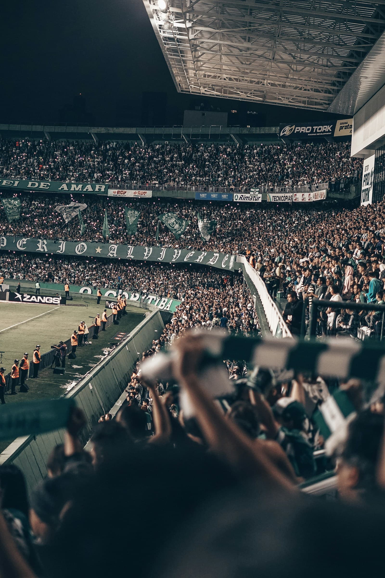 Supporters fill the stands around a floodlit football pitch